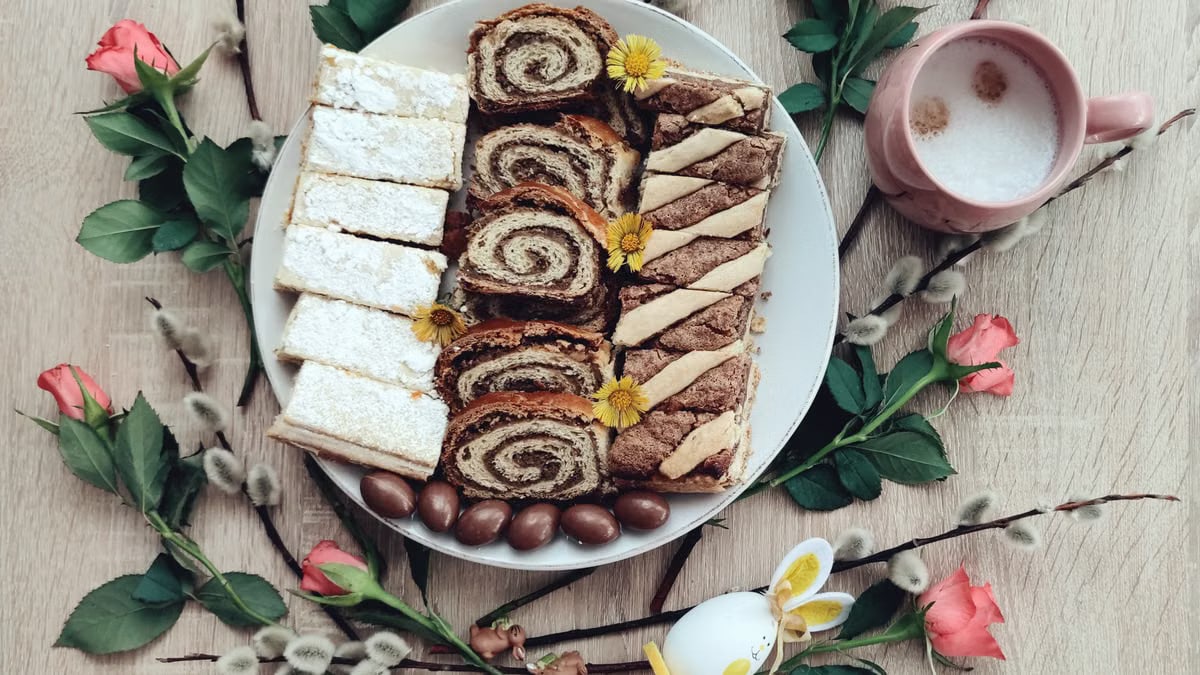 Top view of Easter desserts on a plate with coffee and spring flowers for a festive setting.